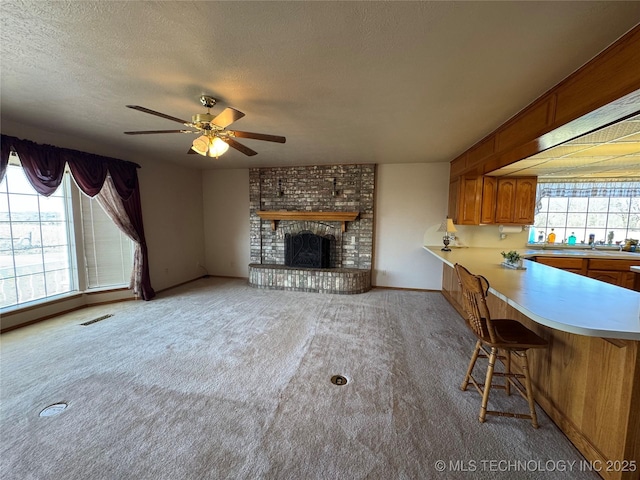 unfurnished living room with light colored carpet, visible vents, a fireplace, and a textured ceiling