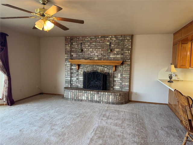 unfurnished living room with carpet floors, a fireplace, a ceiling fan, and baseboards