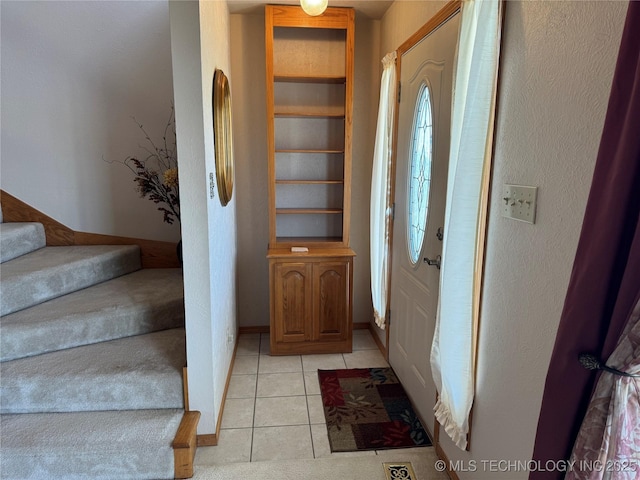 foyer entrance featuring stairs and light tile patterned floors