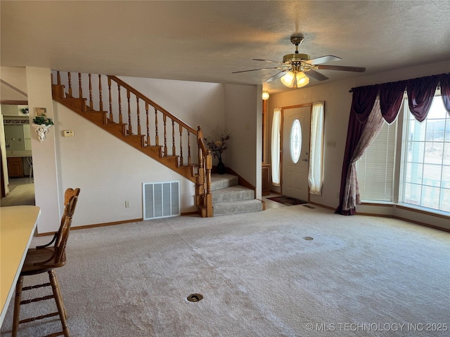 foyer entrance with visible vents, stairway, carpet flooring, and a textured ceiling