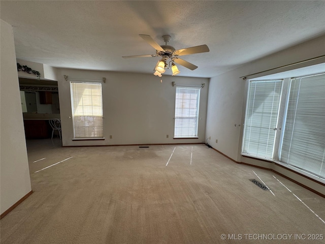 spare room featuring a healthy amount of sunlight, baseboards, visible vents, and a textured ceiling