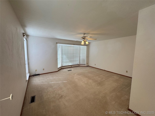 spare room featuring a ceiling fan, carpet flooring, visible vents, and baseboards