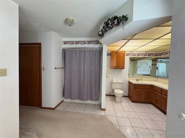 bathroom with a textured ceiling, toilet, vanity, baseboards, and tile patterned floors