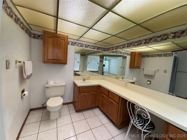 bathroom with a drop ceiling, vanity, toilet, and tile patterned floors