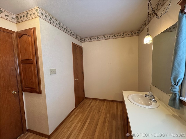 bathroom with baseboards, wood finished floors, and vanity