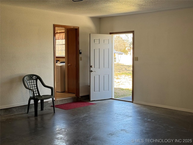 entrance foyer with a healthy amount of sunlight, washer / dryer, a textured ceiling, and concrete flooring