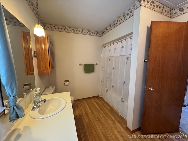 full bathroom with shower / tub combo with curtain, toilet, vanity, wood finished floors, and baseboards