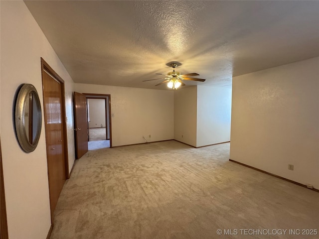 empty room with a textured ceiling, ceiling fan, light carpet, and baseboards