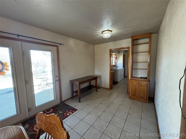 doorway featuring a textured ceiling, light tile patterned flooring, and washing machine and dryer