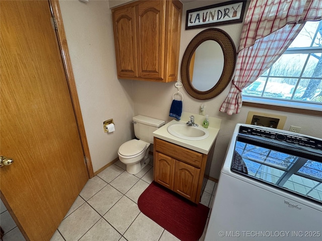 half bathroom featuring baseboards, toilet, washer / clothes dryer, tile patterned floors, and vanity