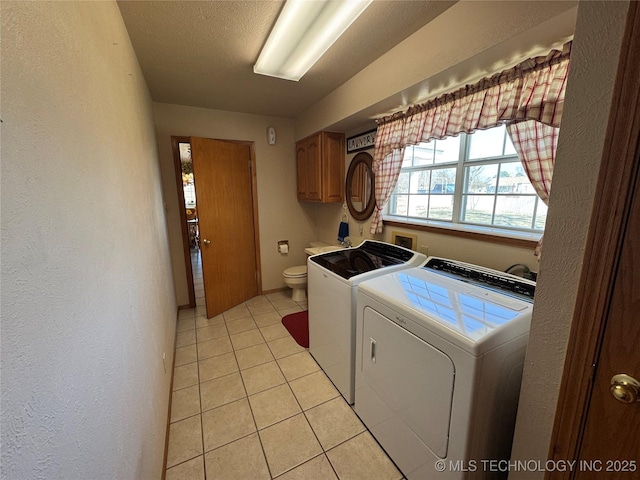 laundry room featuring light tile patterned floors, a textured wall, a textured ceiling, and washing machine and clothes dryer