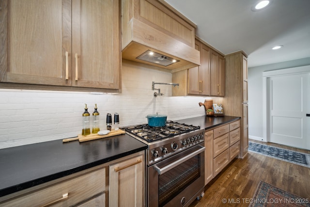 kitchen featuring high end stove, custom exhaust hood, tasteful backsplash, dark countertops, and dark wood finished floors