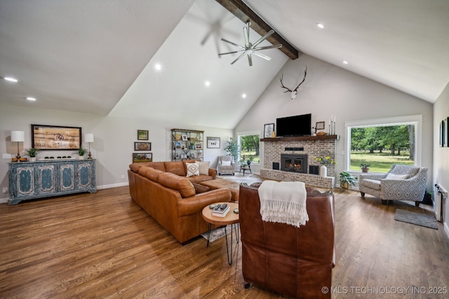 living room featuring a brick fireplace, beam ceiling, a wealth of natural light, and wood finished floors