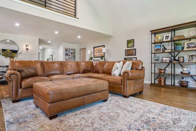 living area with baseboards, high vaulted ceiling, wood finished floors, and recessed lighting