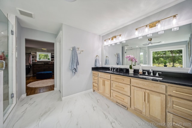 bathroom with marble finish floor, visible vents, a spacious closet, a sink, and a shower stall