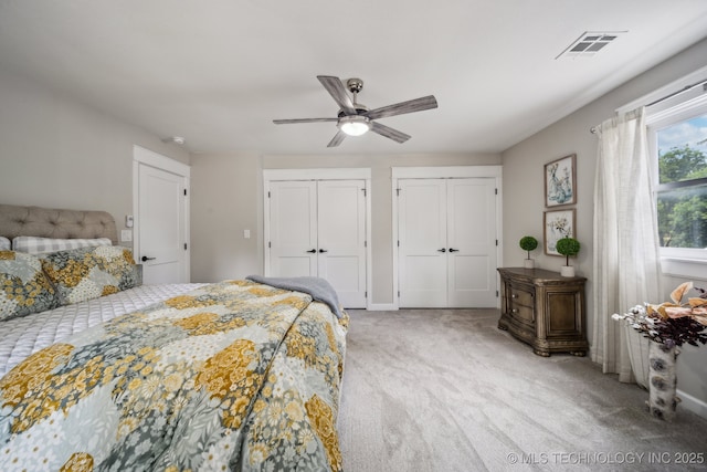 bedroom featuring a ceiling fan, carpet, visible vents, and two closets