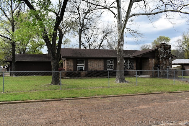 view of front of house with a fenced front yard, a chimney, a front lawn, and brick siding