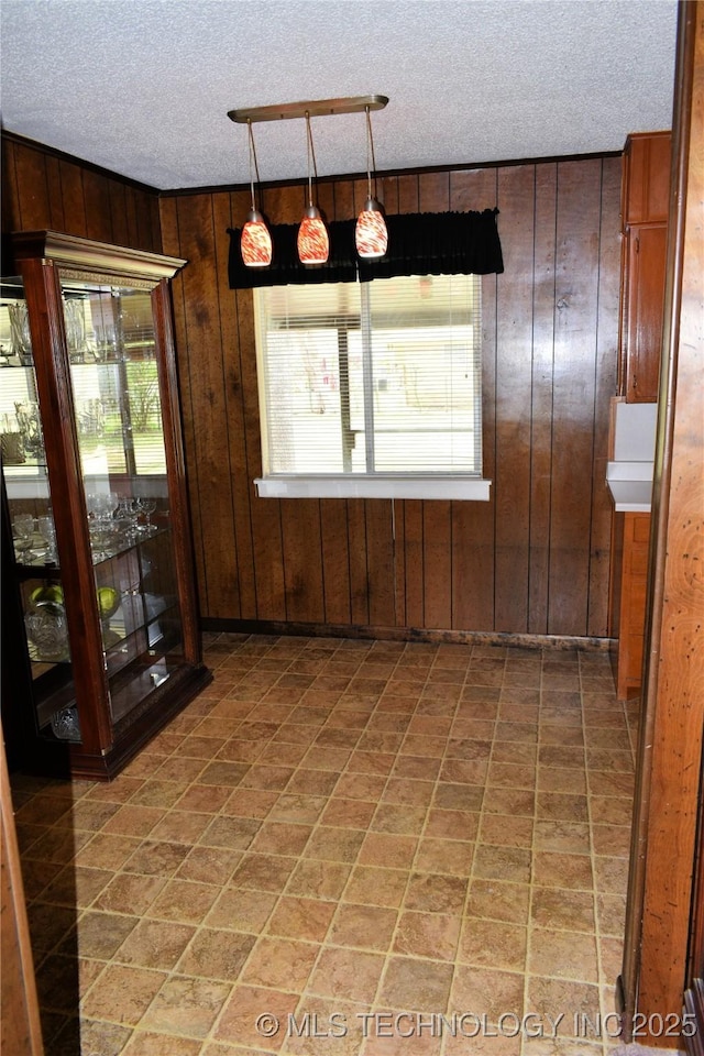 unfurnished dining area with wood walls and a textured ceiling