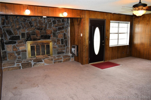 entrance foyer with wooden walls, carpet floors, a fireplace, and heating unit