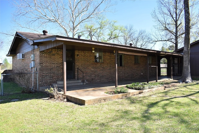 view of side of property with an attached carport, brick siding, a lawn, and a patio