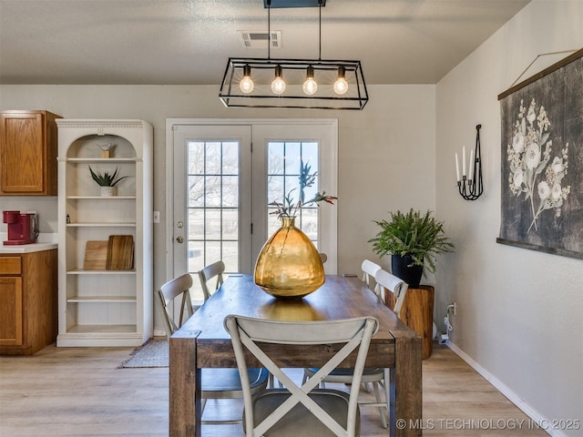 dining room featuring visible vents, light wood-type flooring, and baseboards