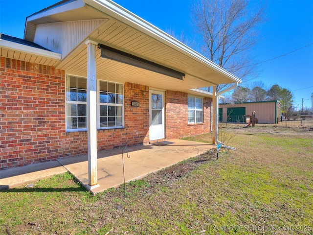 exterior space with a yard, brick siding, and a patio area