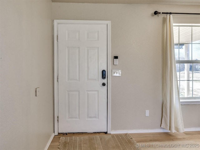 doorway to outside featuring baseboards and light wood-style floors