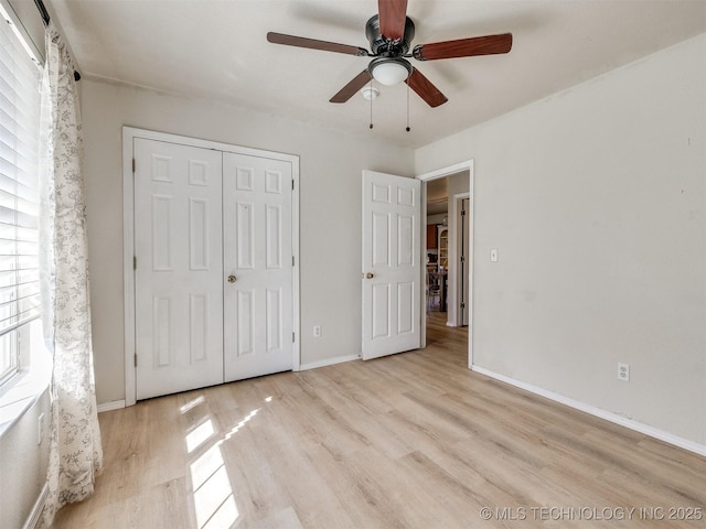 unfurnished bedroom featuring a closet, baseboards, wood finished floors, and a ceiling fan