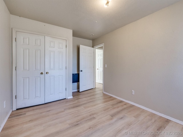 unfurnished bedroom with a closet, baseboards, and light wood-style floors