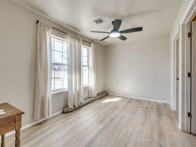 unfurnished room with baseboards, visible vents, light wood finished floors, ceiling fan, and a textured ceiling