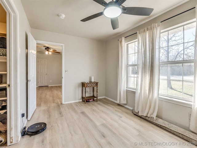 spare room featuring light wood-type flooring, baseboards, and a healthy amount of sunlight