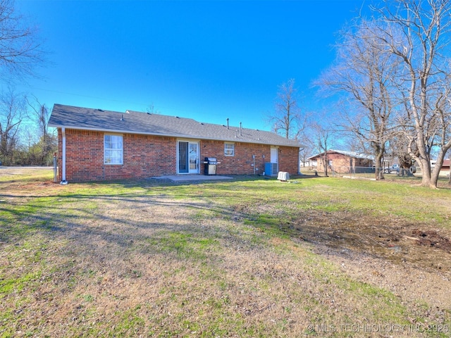 back of property featuring a patio area, a lawn, and brick siding