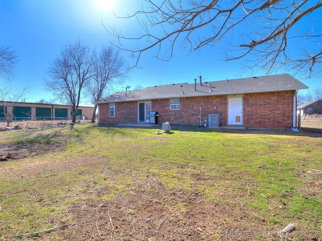 back of house with brick siding and a yard