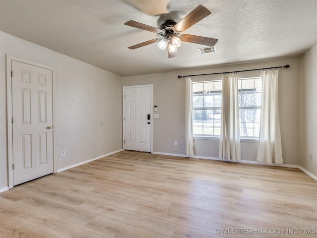 interior space featuring light wood-type flooring, a textured ceiling, and visible vents