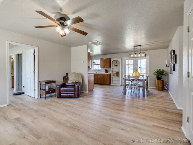 interior space featuring visible vents, light wood-style floors, ceiling fan, and a textured ceiling