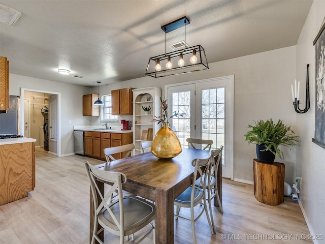 dining room with visible vents, a textured ceiling, baseboards, and light wood-style floors