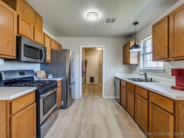 kitchen with visible vents, light wood-type flooring, light countertops, appliances with stainless steel finishes, and a sink