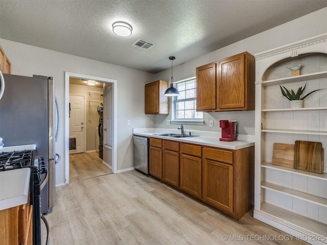 kitchen with visible vents, dishwasher, range with gas stovetop, brown cabinetry, and a sink