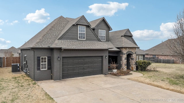 view of front of property featuring brick siding, a shingled roof, central AC, fence, and driveway