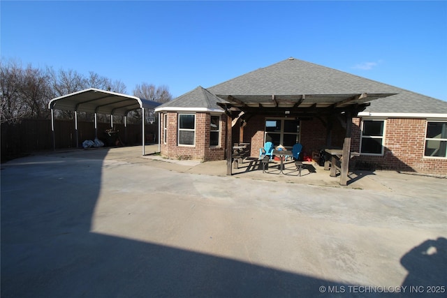 back of property featuring brick siding, roof with shingles, and a detached carport