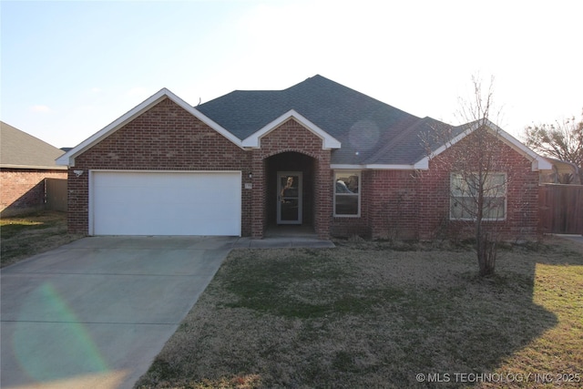 ranch-style home featuring a garage, driveway, a shingled roof, brick siding, and a front yard