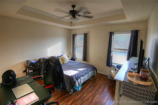 bedroom with ornamental molding, a raised ceiling, visible vents, and wood finished floors