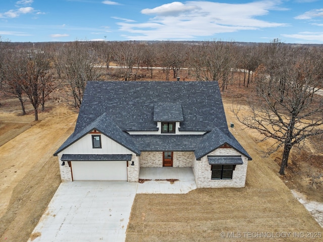 view of front facade featuring a garage, stone siding, a shingled roof, and concrete driveway