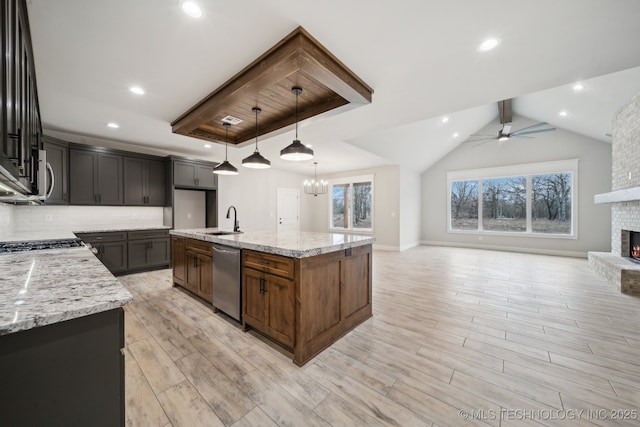 kitchen featuring a fireplace, decorative backsplash, appliances with stainless steel finishes, open floor plan, and a sink