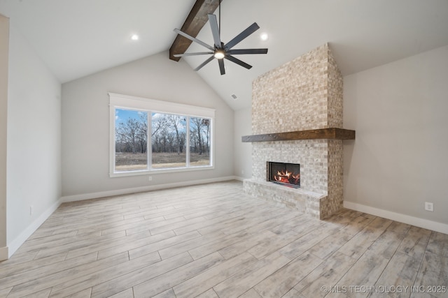 unfurnished living room featuring lofted ceiling with beams, a ceiling fan, a brick fireplace, wood finished floors, and baseboards