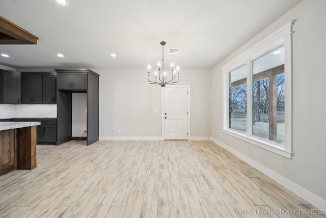 kitchen featuring light wood finished floors, baseboards, decorative backsplash, an inviting chandelier, and recessed lighting