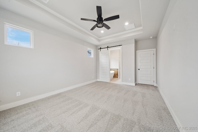 unfurnished bedroom featuring a barn door, baseboards, light colored carpet, a tray ceiling, and recessed lighting