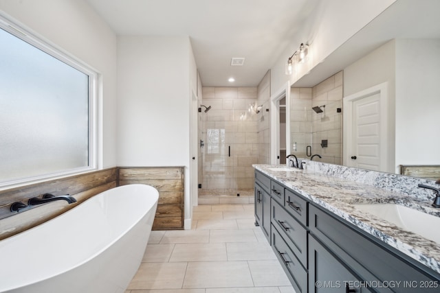 bathroom with double vanity, a freestanding bath, a stall shower, a sink, and tile patterned floors