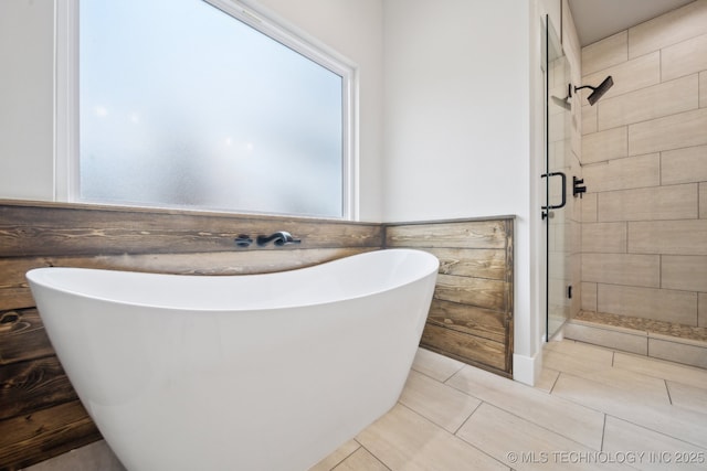 full bathroom featuring a shower stall, tile walls, a freestanding bath, and tile patterned floors