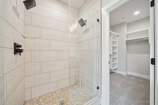 bathroom with a spacious closet, a stall shower, visible vents, and baseboards